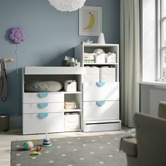 a baby's room with blue walls and white furniture