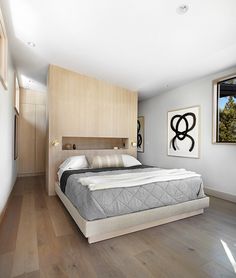 a bed sitting inside of a bedroom on top of a hard wood floor next to a window