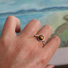 A small round cut of the tiger's eye stone stands out in this sterling silver ring. The array of warm brown tones makes this ring fabulously unique. Wear this ring on its own or layered with your other favourites for a stacked look. Available in three sizes. Clean the sterling silver band with a jewellery polishing cloth. Polish the semi-precious stone with a gems cleanser.  Store in a safe place to avoid scratching.