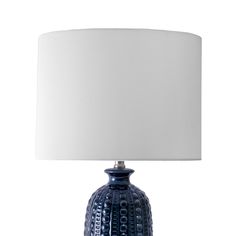 a blue table lamp with a white shade on the top and bottom, in front of a white background