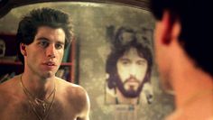 a man with no shirt looking at himself in front of a mirror that has jesus on it