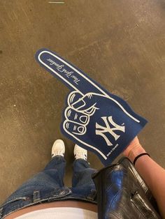 someone is holding up a new york yankees baseball bat shaped towel on the ground in front of their feet