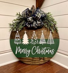 a merry christmas sign hanging on the side of a house with pine trees and evergreens