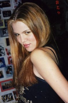 a woman with long hair standing in front of a wall