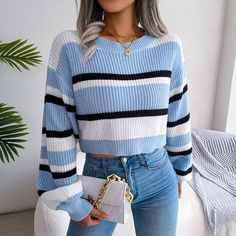 a woman with grey hair wearing a blue and white striped sweater, jeans and heels