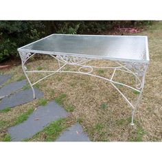 a metal table sitting on top of a grass covered field next to a stone walkway