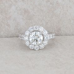 a white gold ring with an oval cut diamond surrounded by smaller round diamonds