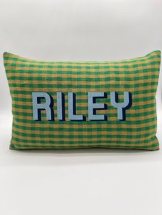 a green and yellow pillow with the word riley embroidered on it's front side