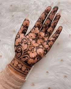 a henna tattoo on someone's hand with brown and pink flowers all over it