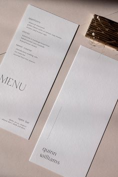 two white menu cards sitting next to each other on top of a table with string