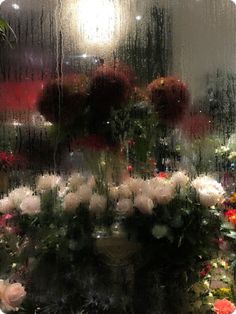 a bunch of flowers that are sitting in front of a glass window on a rainy day