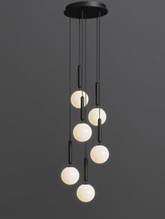 a chandelier with five white balls hanging from it's black metal frame