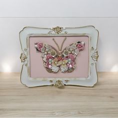 a pink and white frame with a butterfly made out of flowers on top of it