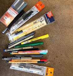 several pens and pencils are lined up on the floor next to some other items