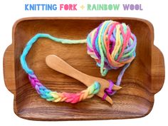 a ball of yarn and a wooden crochet hook on a tray with text overlay reading knitting fork rainbow wool