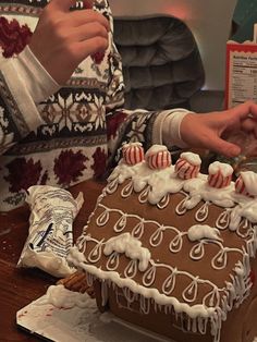 a person decorating a gingerbread house with icing and candy canes on it