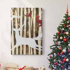 a decorated christmas tree in front of a painting on the wall with birds and deer