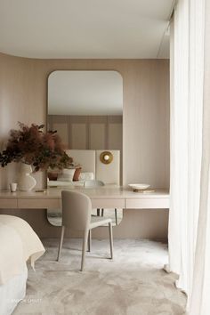 a bedroom with a desk, mirror and chair next to a bed in front of a window