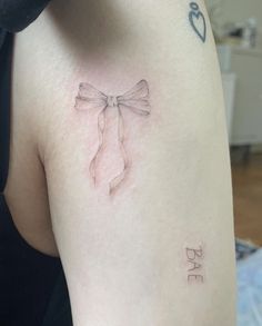 a woman's arm with a bow tattoo on the left side of her body