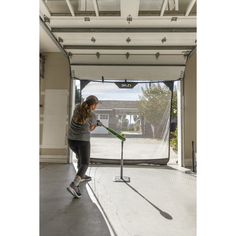 a woman cleaning the floor with a mop in front of an open garage door