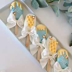 some kind of cake pops in a box with white bows and honeycombs on them