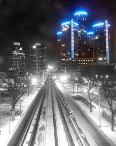 the city skyline is lit up at night in black and white, with snow on the ground