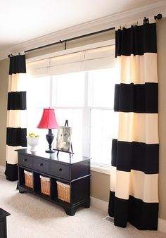 a black and white striped curtain hangs in front of a window with two lamps on it