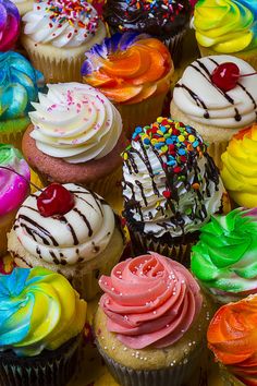 many different colored cupcakes with sprinkles and toppings on them