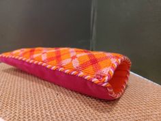 an orange and pink pillow sitting on top of a table