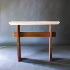 a white table sitting on top of a gray floor next to a wall with a wooden frame