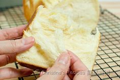 two hands holding a piece of bread on a cooling rack