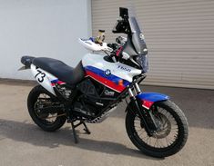 a white and blue motorcycle parked next to a garage door in front of a building