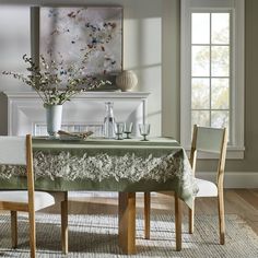 a dining room table and chairs with a green table cloth on it, in front of a fireplace