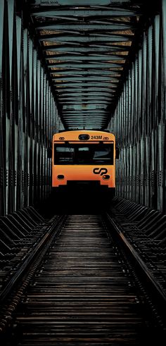 an orange and black bus is going through a tunnel with metal bars on either side