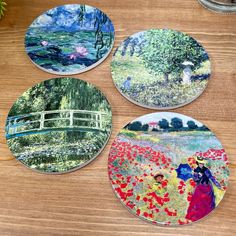 four coasters with paintings on them sitting on a table