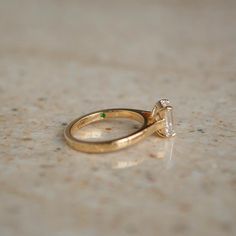 a close up of a gold ring with a diamond on the top and an emerald in the middle