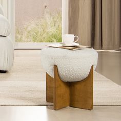 a white ottoman sitting on top of a wooden table next to a bed in a bedroom