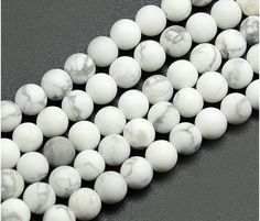 three strands of white marble beads on a black surface, with one strand in the middle