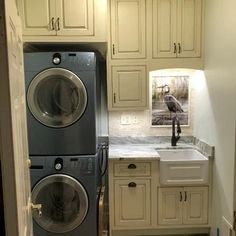 a washer and dryer in a small room with white cabinets on the walls