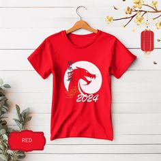 Chinese New Year Shirt, ideal to celebrate the year of the dragon. ~ About this T-shirt: Adult Unisex T-shirts: Soft cotton, great quality, light fabric with 100% Airlume combed and ringspun cotton, fiber content may vary for different colors. Ribbed knit collars to bolster shaping. Runs true to size. ~ Returns, Exchanges & Cancellations When you place an order, we customize the item and send it to production. Therefore, we cannot accept returns, exchanges or cancellations at this point. If you made a mistake on your personalization text or need to change the text, please contact us within 2 hours of placing your order. ~ Care Instructions Machine wash cold (max 30C or 90F), do not bleach, do not tumble dry, do not iron, do not dry clean.  ~ Notes The position of the design, as well as the Red Short Sleeve T-shirt For Gift, Red Short Sleeve T-shirt For Gifting, New Year Red T-shirt With Graphic Print, Red Graphic Print T-shirt For New Year, Red Short Sleeve Shirt For Gift, Red Short Sleeve Shirt As Gift, New Year Graphic Print Short Sleeve T-shirt, Red Short Sleeve T-shirt For New Year, China New Year