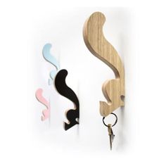 three decorative wooden hooks hang from the wall, one has a key and two are shaped like swirls