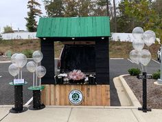 a small booth with balloons and decorations on the side of it in front of a parking lot