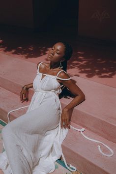 a woman in a white dress sitting on some steps