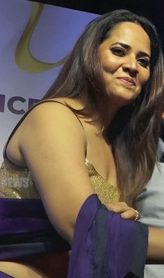 a woman in a gold and purple dress sitting on a chair with her arm around another woman's shoulder