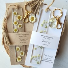 three key chains with daisies attached to them on top of a piece of paper