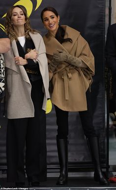 two women standing next to each other in front of a sign