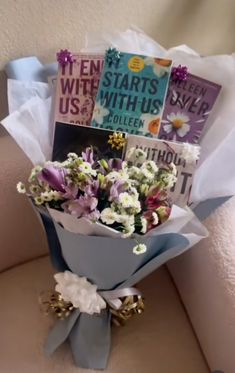 a bouquet of flowers sitting on top of a couch next to a card board and magazine