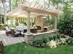 an outdoor living area with stone fireplace and seating