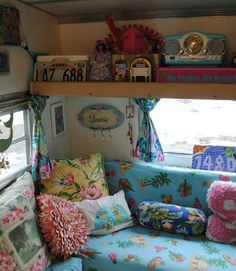 the inside of a camper with lots of pillows and decorations on top of it