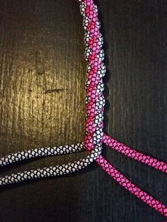 the pink and white string is attached to a black cord with silver dots on it